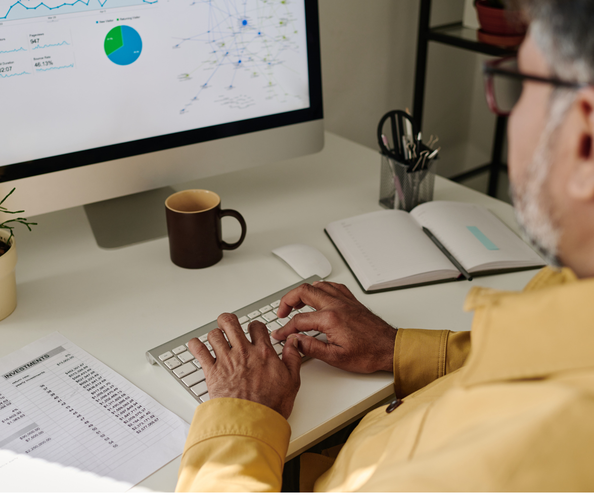 Imagem mostra um homem em frente ao computador analisando dados